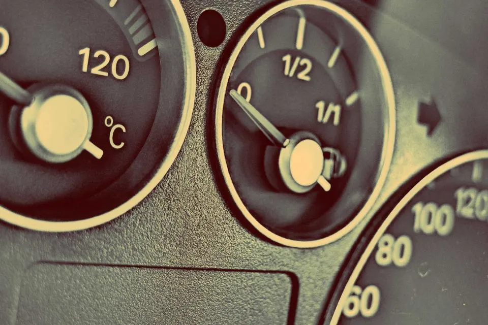 Gros plan sur un tableau de bord de voiture, l'aiguille de la jauge de carburant proche du zéro.