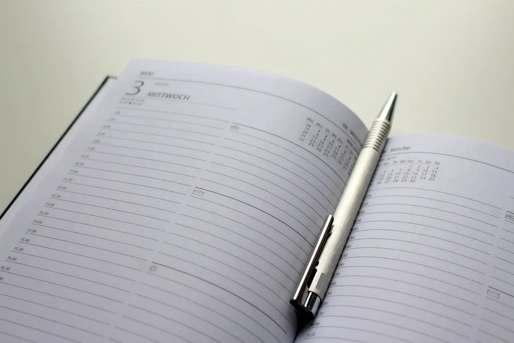 Agenda ouvert sur une page datée, stylo en métal posé dessus.