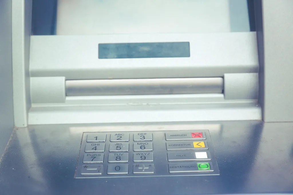 Gros plan sur le clavier et la fente d'un distributeur automatique de billets.