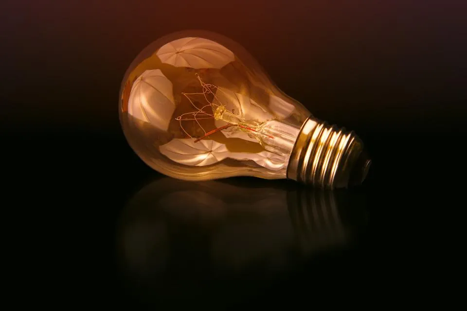 Ampoule à filament allumée, couchée sur une surface sombre.