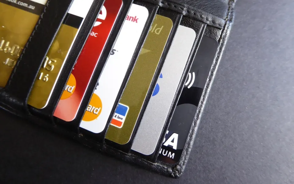 Portefeuille en cuir noir ouvert, une rangée de cartes bancaires glissées dans ses fentes.