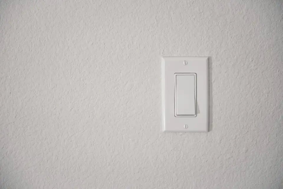 Interrupteur blanc sur un mur clair.