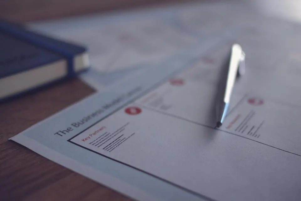 Stylo posé sur un document imprimé, carnet en arrière-plan.