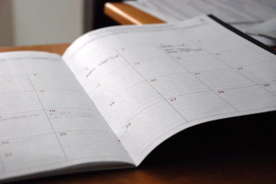 Agenda mensuel ouvert sur un bureau en bois, les cases des jours encore presque vides.