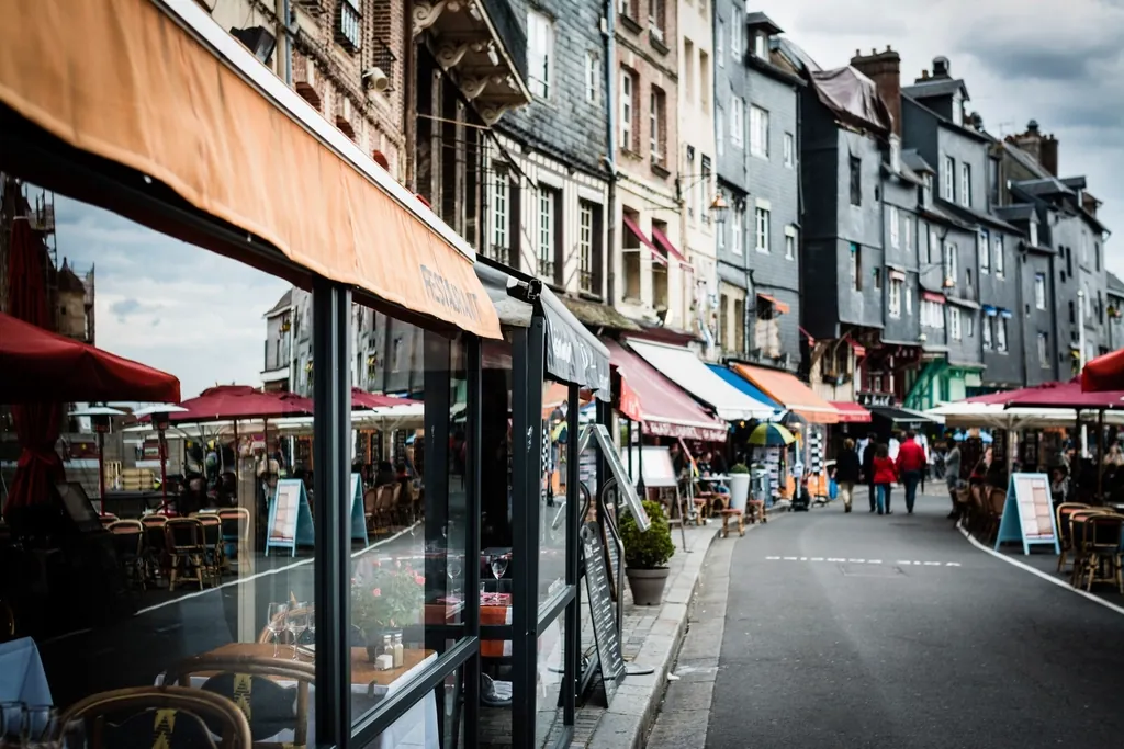 Rue commerçante d'une ville normande, hautes maisons à façades d'ardoise, terrasses et stores.