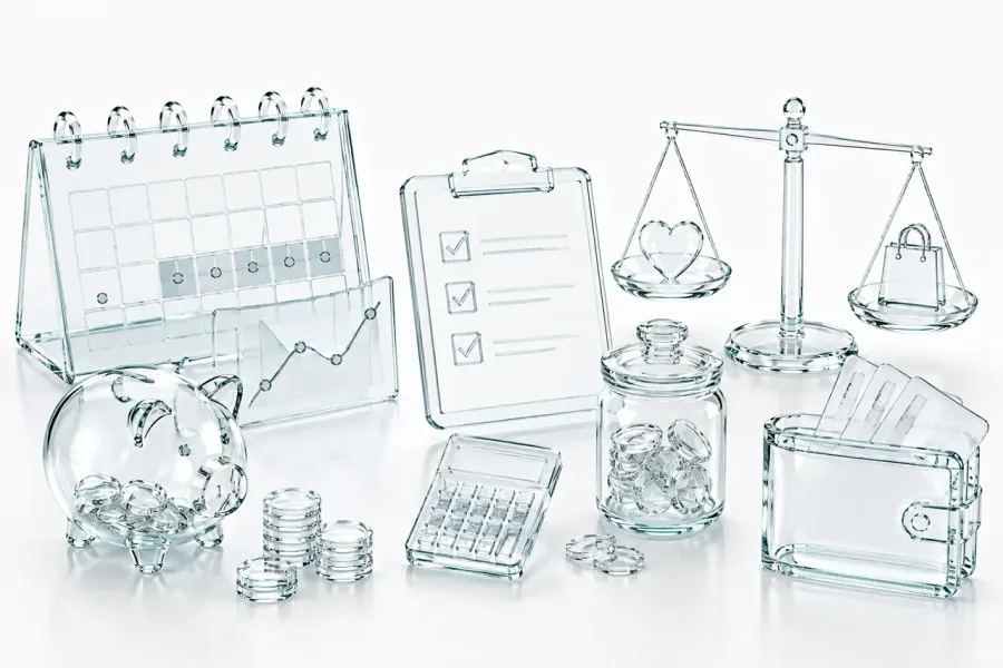Objets en verre alignés sur fond clair : calendrier, courbe de solde, tirelire, calculatrice, bocal de pièces et portefeuille, l'attirail d'une trésorerie qu'on regarde à l'avance.
